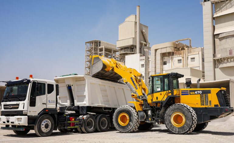 A large truck parked beside a big dump truck, showcasing their size and utility in a construction area.