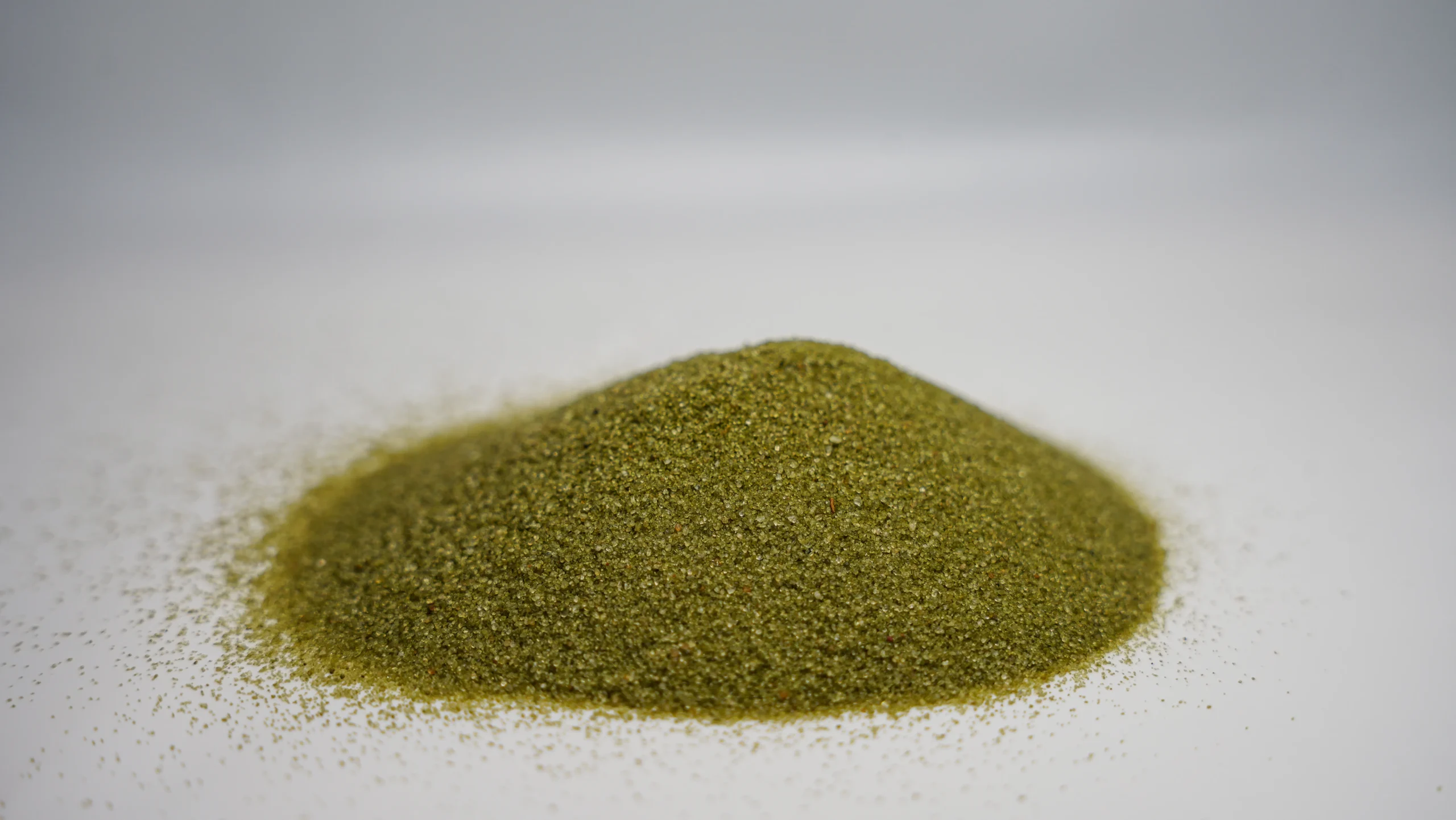 A small pile of green granular sand